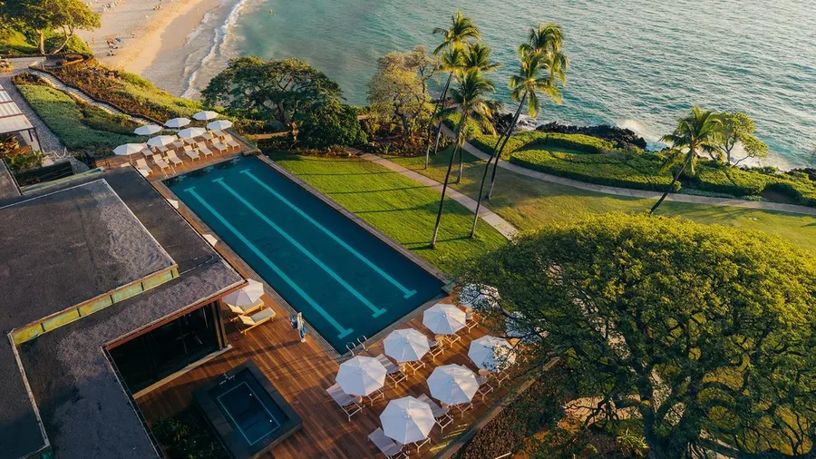 Aerial view of an oceanfront lap pool and lawn above the beach at Mauna Kea Resort